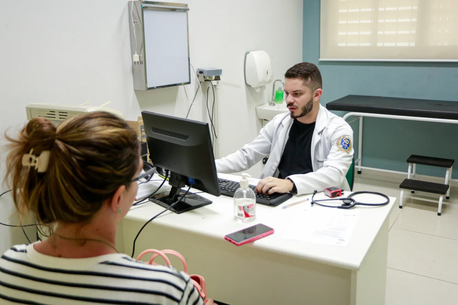 a man in a white coat sitting at a desk with a woman in a striped shirt