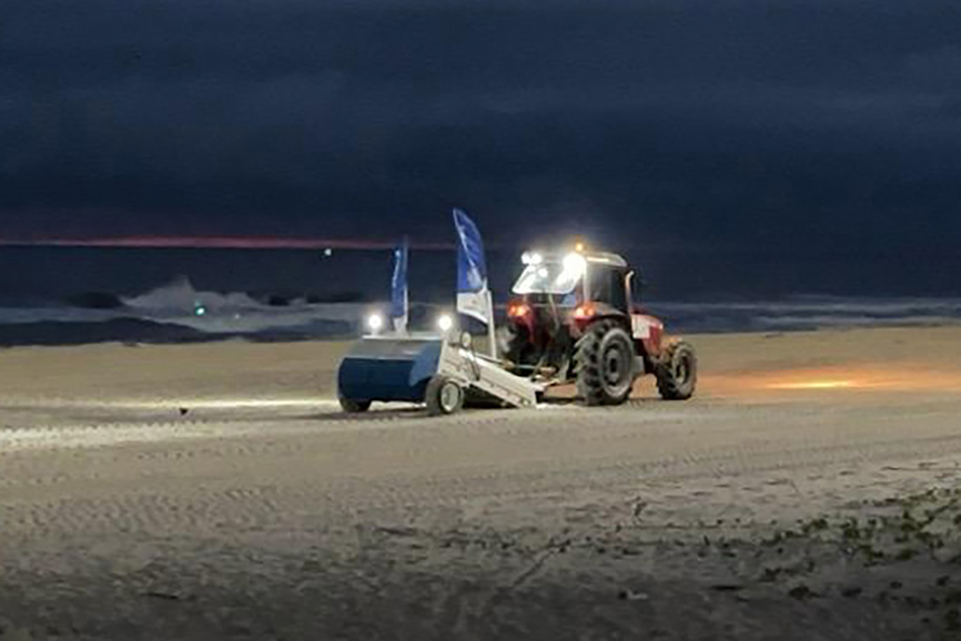 Máquina saneadora inicia limpeza da areia da praia